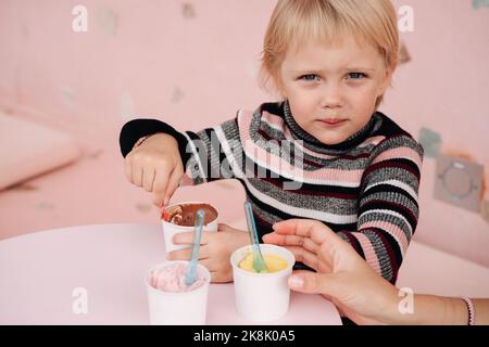 Kinder essen Eis in einem Café. Set von Schüsseln mit verschiedenen Eiscreme mit verschiedenen Geschmacksrichtungen und frischen Zutaten Stockfoto