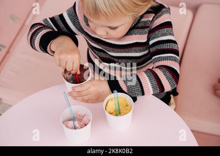 Kinder essen Eis in einem Café. Set von Schüsseln mit verschiedenen Eiscreme mit verschiedenen Geschmacksrichtungen und frischen Zutaten Stockfoto