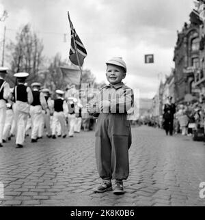 Oslo 19560517. Mai 17 in Oslo. Glücklicher kleiner Junge mit Flagge schaut auf den Zug auf dem Weg zum Karl Johans Tor. Ein bisschen Warze scheint der Stimmung keinen Dämpfer zu geben. Music Corps / Boy Music Corps im Hintergrund. Foto: NTB / NTB Oslo 19560517. Unabhängigkeitstag in Norwegen. Ein glücklicher Junge mit der norwegischen Flagge beobachtet die Parade, die auf der Umzugsstraße karl johan in oslo vorgeht. Foto: NTB/ NTB Stockfoto