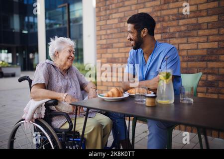 Pfleger beim Frühstück mit seinem Kunden im Café. Stockfoto