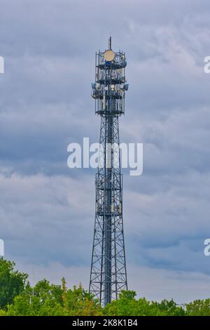 Ein Telekommunikationsturm mit vielen Antennen, Stahlgerüst und blauem bewölktem Himmel Stockfoto
