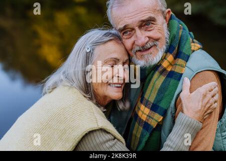 Das verliebte Senioren-Paar umarmt sich in der herbstlichen Natur. Stockfoto