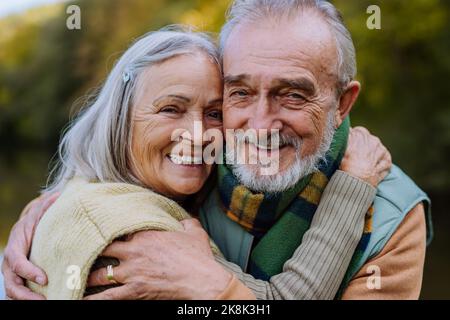 Das verliebte Senioren-Paar umarmt sich in der herbstlichen Natur. Stockfoto