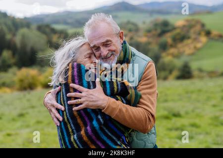 Das verliebte Senioren-Paar umarmt sich in der herbstlichen Natur. Stockfoto