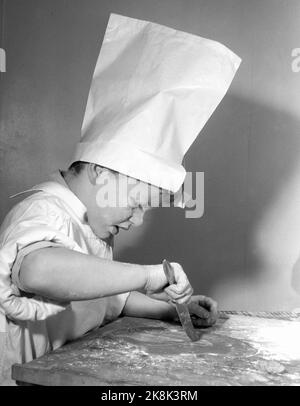 Oslo Weihnachten 1958. Kinder backen Lebkuchen. Eines Tages während der Weihnachtszeit interessierten sich die Jungen der Mutter plötzlich für häusliche Aktivitäten und begannen, die Küche zu benutzen, die den Mädchen vorbehalten war. Drei Brüder werden zu Weihnachten Lebkuchenmänner machen. Ein Bäcker ist kein Bäcker ohne Schürze und Backhut Papa's Shirt und eine weiße Papiertüte hat den Dienst getan. Das Ergebnis des Backens war so erfolgreich, dass kein Lebkuchen in die Box kam. Sie gingen im Magen der Bäcker. Die Gesichter bekamen mehr Runden mit Mehl als mit Leiben. Foto: Aage Storløkken NTB / NTB Stockfoto