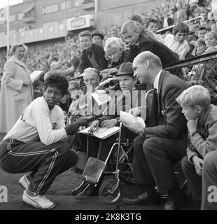 Oslo 19620828 der amerikanische Leichtathletik-Star Wilma Rudolph, der während der Olympischen Spiele in Rom 1960 drei Goldmedaillen gewann, besucht Norwegen. Hier schreibt sie Autogramme für einen Jungen im Rollstuhl, in Bislett während einer Leichtathletik-Veranstaltung. Foto: NTB / NTB Stockfoto