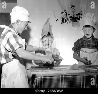 Oslo Weihnachten 1958. Kinder backen Lebkuchen. Eines Tages während der Weihnachtszeit interessierten sich die Jungen der Mutter plötzlich für häusliche Aktivitäten und begannen, die Küche zu benutzen, die den Mädchen vorbehalten war. Drei Brüder werden zu Weihnachten Lebkuchenmänner machen. Ein Bäcker ist kein Bäcker ohne Schürze und Backhut. Das Hemd des Vaters und eine weiße Papiertüte waren der Service. Das Ergebnis des Backens war so erfolgreich, dass kein Lebkuchen in die Box kam. Sie gingen im Magen der Bäcker. Die Gesichter bekamen mehr Runden mit Mehl als mit Leiben. Foto: Aage Storløkken NTB / NTB Stockfoto