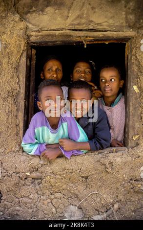 Äthiopien, Porträt einer Familie, die aus dem Fenster ihres adobe-Hauses schaut. Stockfoto