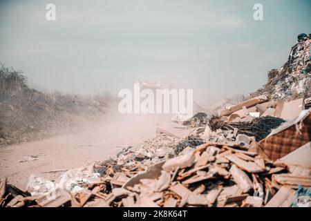 Nachweis menschlicher Fahrlässigkeit. Auf dem Bild großer Haufen Müll ruiniert die Natur. Im Hintergrund Müllwagen. Stockfoto