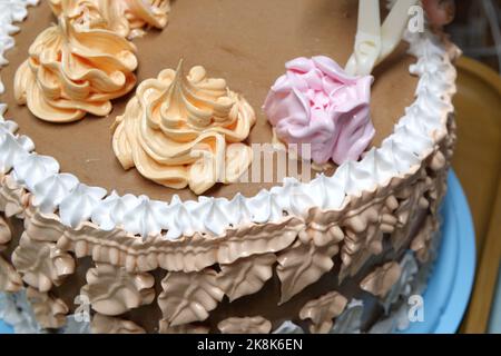 Die Konditorin gießt mit dem Gebäckbeutel, Nahaufnahme, Creme auf den Biskuitkuchen. Konditor ist Kochen hausgemachten Kuchen. Kochen, Backen und Kochen, Stockfoto