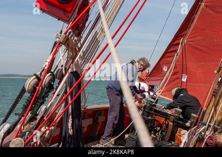 Die Crew arbeitet an Bord des traditionellen Gaffelschneiders „Jolie Brise“ in Solent, Hampshire, Großbritannien Stockfoto