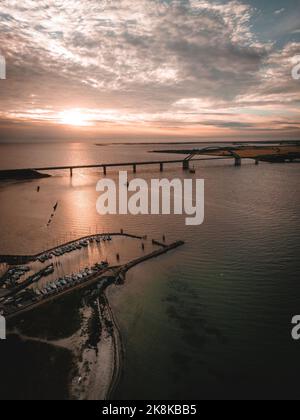 Eine vertikale Aufnahme der Fehmarn Sound Bridge in der Ostsee bei malerischem Sonnenuntergang mit Wolken, Deutschland Stockfoto