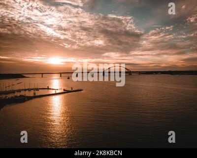 Ein schöner Blick auf die Fehmarn Sound Bridge in der Ostsee bei einem dramatischen Sonnenuntergang mit Wolken, Deutschland Stockfoto