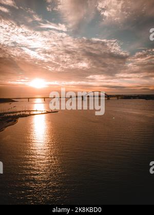 Eine vertikale Aufnahme der Fehmarn Sound Bridge in der Ostsee bei malerischem Sonnenuntergang mit Wolken, Deutschland Stockfoto