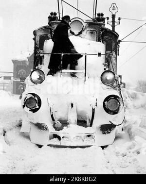 Kragerø 19540320. Südnorwegen steht kurz vor dem Erwürgen durch Schnee. Im Februar kippte der Schnee 23 Tage lang Tag und Nacht. Straßen waren blockiert, Züge schneiten hinein, Autos verschwanden unter den Schneemassen, an vielen Stellen fast nur der Schornstein, der über den Häusern hing. Der Schnee lag meterhoch in den Straßen und der Schnee Tag und Nacht. Die Menschen kämpften als Terrier, um die Hauptlinie offen zu halten. Im Schnee versuchten die Züge auf der Sørlandsbanen, voranzukommen. Foto: Aage Storløkken / Aktuell / NTB Stockfoto