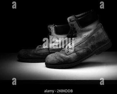 Walking alt, Arbeitsstiefel, schwarz-weiß einfarbig. Stockfoto