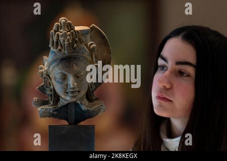 London, Großbritannien. 24. Oktober 2022. Ein Mitarbeiter sieht „Einen Gupta-Terrakotta-Kopf einer Gottheit“, Nordindien, 5.. Jahrhundert, (Est. £7.000 - £9.000) bei der Vorschau auf Bonhams Islamic and Indian Art Sale. Am 25. Oktober werden in Bonhams New Bond Street Galerien 157 Lose versteigert. Quelle: Stephen Chung / Alamy Live News Stockfoto