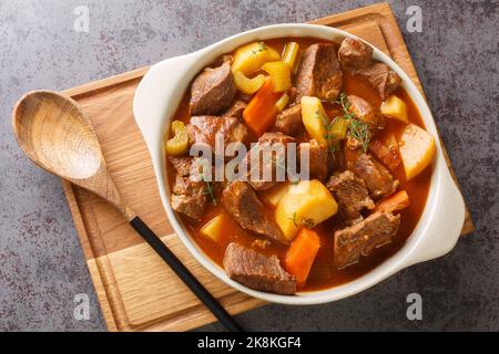 Herzhafter irisch inspirierter Rindereintopf mit Knoblauch, Brühe, Guinness, Speck, Kartoffeln, Karotten und Zwiebeln in den Topf auf dem Tisch. Horizontal zu Stockfoto