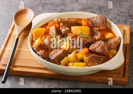 Herzhafter irisch inspirierter Rindereintopf mit Knoblauch, Brühe, Guinness, Speck, Kartoffeln, Karotten und Zwiebeln in den Topf auf dem Tisch. Horizontal Stockfoto