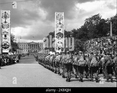 Oslo 19450609 Friedenstage 1945. Home Front Day. Die Heimatfront pariert das Karl Johans Tor zum Schloss hinauf und wird von großen Menschenmengen abgelehnt. Hier ist eine Firma Home Front Soldaten mit Rucksäcken auf dem Weg zum Schloss. Die Dekorationen, die bis zur Rückkehr des Königs aufgestellt wurden, schmücken noch immer die Straße. Foto: NTB / NTB Stockfoto