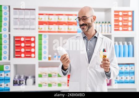 Junger hispanic-Mann Apotheker hält Pillen Flaschen in der Apotheke Stockfoto