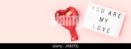 Du bist meine Liebe - Zitat. Banner mit rotem Herz-Folienballon und Leuchtkasten auf rosa Hintergrund. Stockfoto