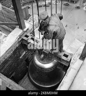 Oslo 19500424 Bau des Osloer Rathauses. Die Rathausuhren sind an Ort und Stelle gehisst. Eine der riesigen Uhren wird angehoben, und einer der Arbeiter ist dabei, sie zu montieren. Er hat einen gefährlichen Arbeitsplatz. Th. Der Hinterhof des Rathauses ist tief im Blick, und es scheint nicht, dass er irgendeine Art von Sicherung hat, wo er auf einem Balken balanciert, der die Uhr hält. Foto: NTB / NTB Stockfoto