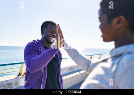 Mann und Frau tragen Sportkleidung mit hohen fünf Händen am Meer angehoben Stockfoto
