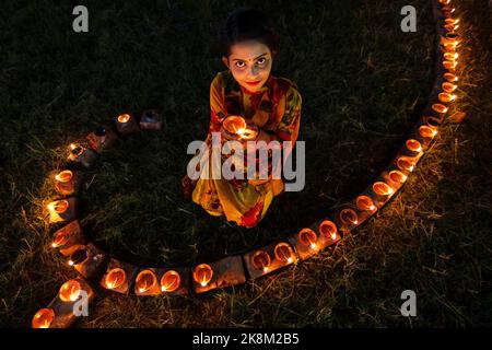 Narayanganj, Dhaka, Bangladesch. 24. Oktober 2022. Hindu-Anhänger beleuchten ''Diyas'' (irdene Lampen) auf einem Rangoli, einem Rahmen aus dekorierten Mustern, als Teil der Diwali-Feierlichkeiten in einem Tempelgelände in Narayanganj, Bangladesch. Viele leichte Öllampen oder Kerzen symbolisieren den Sieg des Lichts über die Dunkelheit, und im Rahmen der Feierlichkeiten werden Feuerwerke aufgesetzt. Das Festival findet jedes Jahr nach dem hinduistischen Mondkalender statt. Das Wort ''Diwali'' leitet sich vom Sanskrit-Wort ''Deepavali'' ab, was eine Reihe von beleuchteten Lampen bedeutet; daher ist es auch als das Fest der Lichter bekannt. Diwali i. Stockfoto