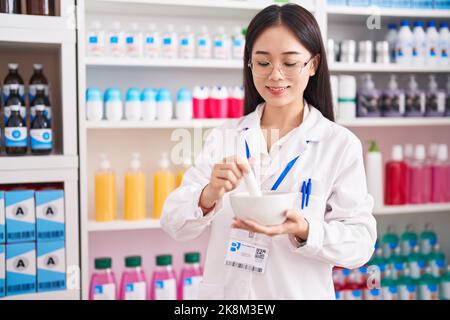 Junge chinesische Frau Apotheker lächelnd zuversichtlich machen Mischung in der Apotheke Stockfoto