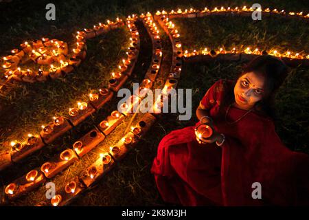 Narayanganj, Dhaka, Bangladesch. 24. Oktober 2022. Hindu-Anhänger beleuchten ''Diyas'' (irdene Lampen) auf einem Rangoli, einem Rahmen aus dekorierten Mustern, als Teil der Diwali-Feierlichkeiten in einem Tempelgelände in Narayanganj, Bangladesch. Viele leichte Öllampen oder Kerzen symbolisieren den Sieg des Lichts über die Dunkelheit, und im Rahmen der Feierlichkeiten werden Feuerwerke aufgesetzt. Das Festival findet jedes Jahr nach dem hinduistischen Mondkalender statt. Das Wort ''Diwali'' leitet sich vom Sanskrit-Wort ''Deepavali'' ab, was eine Reihe von beleuchteten Lampen bedeutet; daher ist es auch als das Fest der Lichter bekannt. Diwali i. Stockfoto