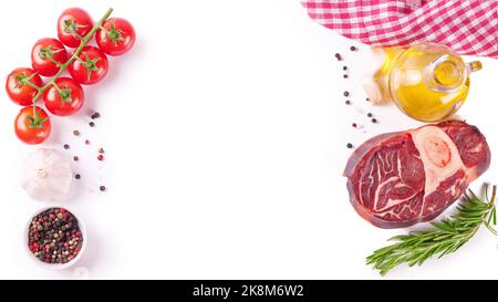 Zutaten zum Kochen. Rohes Rindersteak mit Knochen und Gewürzen, Tomaten, Rosmarin, Knoblauch, Olivenöl isoliert auf weißem Hintergrund mit Kopierraum. Bis Stockfoto