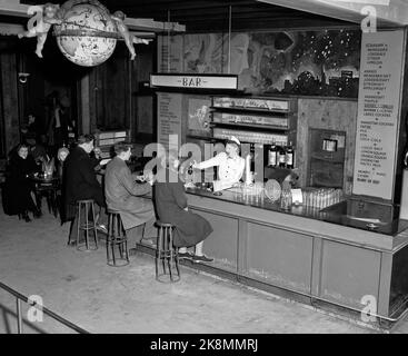 Oslo 19530201 Interieur aus Møllhausen Konditori im Karl Johans Tor. Hier von der Bar-Umgebung. Kunden an der Theke, weibliche Angestellte mit weißer Schürze und Bademantel hinter der Theke. Liste / Zeichen / Menü / Preisliste der Waren an der Wand. Foto: NTB / NTB Stockfoto