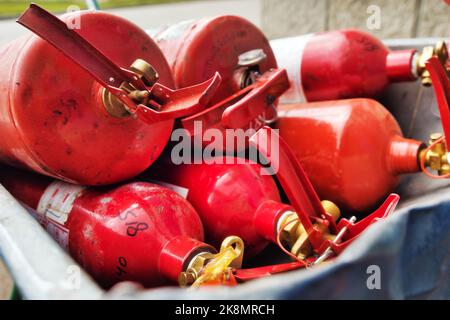 Viele rote Feuerlöscher liegen im Stapel. Feuerlöschanlagen Verteilung der Feuerlöscher für Löschbrände. Stockfoto