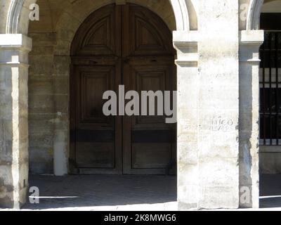 '1764 Nicolas' am 11 Place de Vosges in Paris im Stadtteil Marais, auf einer der Säulen der berühmten Arkaden, können wir sehen, was als eines der ältesten Graffiti in Paris gilt. Auf diesem Graffiti aus dem Jahr 1764, das in den Stein eingraviert ist (was es sicherlich erlaubt hat, ihn bis heute zu erhalten), können wir den Vornamen Nicolas lesen, der der Autor des Graffiti ist, Nicolas Edme Restif de la Breton, ein Schriftsteller. Er schuf sie in ganz Paris und veröffentlichte sie in seinem Buch: 'Es Inscriptions'. Heute ist nur noch das auf dem Place des Vosges erhalten Stockfoto