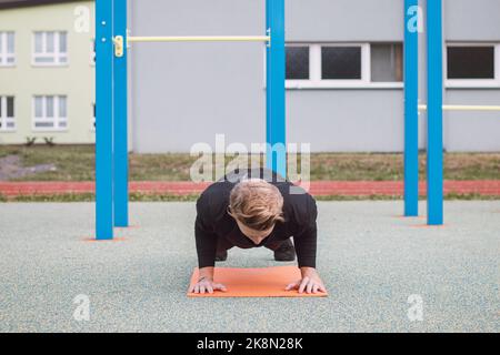 Die blonde Sportlerin führt eine Übung durch, die als Push-up bezeichnet wird. Eine schwere intensive Übung, um die Muskeln des Oberkörpers zu entwickeln. Trainieren Sie mit Ihrem eigenen Körper wi Stockfoto