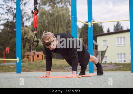 Die blonde Sportlerin führt eine Übung durch, die als Push-up bezeichnet wird. Eine schwere intensive Übung, um die Muskeln des Oberkörpers zu entwickeln. Trainieren Sie mit Ihrem eigenen Körper wi Stockfoto