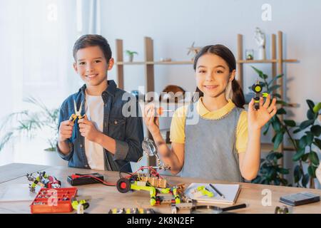 Glückliche Kinder halten Werkzeuge in der Nähe Roboter-Modell auf dem Tisch zu Hause, Stock Bild Stockfoto