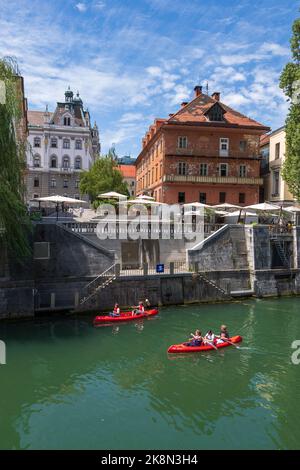 Ljubljana, Slowenien - 14. Juli 2022: Kajaks mit Menschen auf dem Fluss Ljubljanica im Stadtzentrum ist eine Kajak- oder Kanutour ein beliebter Tourist Stockfoto