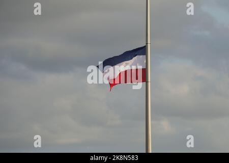 Kopfüber hängende niederländische Flagge an einem Lampenpfosten gegen einen bewölkten Himmel Stockfoto