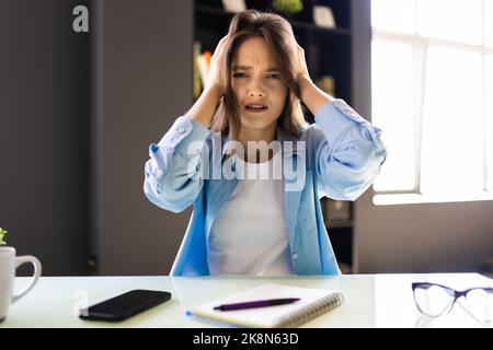 Eine glückliche Frau, die online eine schöne Überraschung erhält, sitzt am Schreibtisch und arbeitet mit ihrem Laptop Stockfoto