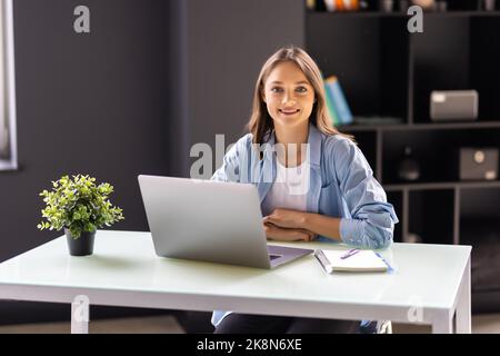 Geschäftsfrau sitzt im Büro mit einem Laptop. Stockfoto