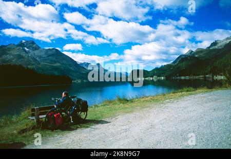 Ein Radfahrer rastet am Silvaplanersee mit Blick auf die Oberengadiner Berglandschaft am Silvaplaner See im Oberenga MACHT EIN Biker eine Pause Stockfoto