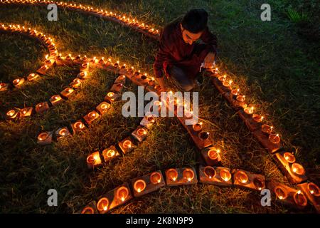 Narayanganj, Dhaka, Bangladesch. 24. Oktober 2022. Hindu-Anhänger beleuchten ''Diyas'' (irdene Lampen) auf einem Rangoli, einem Rahmen aus dekorierten Mustern, als Teil der Diwali-Feierlichkeiten in einem Tempelgelände in Narayanganj, Bangladesch. Viele leichte Öllampen oder Kerzen symbolisieren den Sieg des Lichts über die Dunkelheit, und im Rahmen der Feierlichkeiten werden Feuerwerke aufgesetzt. Das Festival findet jedes Jahr nach dem hinduistischen Mondkalender statt. Kredit: ZUMA Press, Inc./Alamy Live Nachrichten Stockfoto