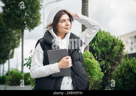 Attraktive junge Frau, die ein Tablet im Freien hält. Stockfoto