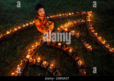 Narayanganj, Dhaka, Bangladesch. 24. Oktober 2022. Hindu-Anhänger beleuchten ''Diyas'' (irdene Lampen) auf einem Rangoli, einem Rahmen aus dekorierten Mustern, als Teil der Diwali-Feierlichkeiten in einem Tempelgelände in Narayanganj, Bangladesch. Viele leichte Öllampen oder Kerzen symbolisieren den Sieg des Lichts über die Dunkelheit, und im Rahmen der Feierlichkeiten werden Feuerwerke aufgesetzt. Das Festival findet jedes Jahr nach dem hinduistischen Mondkalender statt. Kredit: ZUMA Press, Inc./Alamy Live Nachrichten Stockfoto