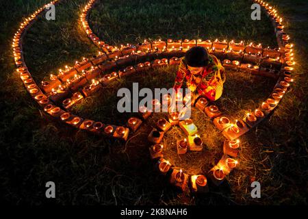 Narayanganj, Dhaka, Bangladesch. 24. Oktober 2022. Hindu-Anhänger beleuchten ''Diyas'' (irdene Lampen) auf einem Rangoli, einem Rahmen aus dekorierten Mustern, als Teil der Diwali-Feierlichkeiten in einem Tempelgelände in Narayanganj, Bangladesch. Viele leichte Öllampen oder Kerzen symbolisieren den Sieg des Lichts über die Dunkelheit, und im Rahmen der Feierlichkeiten werden Feuerwerke aufgesetzt. Das Festival findet jedes Jahr nach dem hinduistischen Mondkalender statt. Kredit: ZUMA Press, Inc./Alamy Live Nachrichten Stockfoto