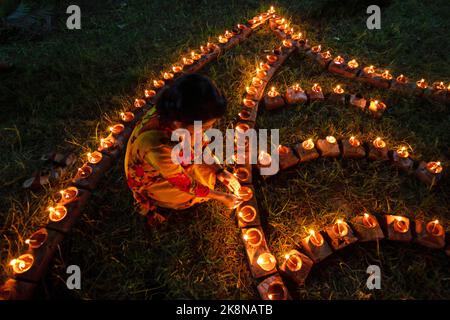 Narayanganj, Dhaka, Bangladesch. 24. Oktober 2022. Hindu-Anhänger beleuchten ''Diyas'' (irdene Lampen) auf einem Rangoli, einem Rahmen aus dekorierten Mustern, als Teil der Diwali-Feierlichkeiten in einem Tempelgelände in Narayanganj, Bangladesch. Viele leichte Öllampen oder Kerzen symbolisieren den Sieg des Lichts über die Dunkelheit, und im Rahmen der Feierlichkeiten werden Feuerwerke aufgesetzt. Das Festival findet jedes Jahr nach dem hinduistischen Mondkalender statt. Kredit: ZUMA Press, Inc./Alamy Live Nachrichten Stockfoto