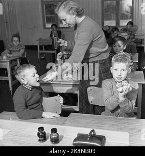 Aurskog 11 February 1956 'Diese Kinder haben 3 Meilen Schulstraße' die jungen Kinder Kjell aus Nybak, Hallvard aus Sinkerud und Marit aus Stenshaugen müssen 6 km allein durch den nächtlichen Schwarzwald laufen, bevor sie den Schulbus in Bekkesaga erreichen. Sie müssen um 5 Uhr aufstehen, um den Bus zu erreichen, der zur Haneborg-Schule in Aurskog fährt. Verteilung von Kabeljau im Klassenzimmer. Foto; Sverre A. Børretzen / Aktuell / NTB Stockfoto