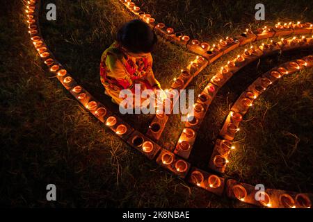 Narayanganj, Dhaka, Bangladesch. 24. Oktober 2022. Hindu-Anhänger beleuchten ''Diyas'' (irdene Lampen) auf einem Rangoli, einem Rahmen aus dekorierten Mustern, als Teil der Diwali-Feierlichkeiten in einem Tempelgelände in Narayanganj, Bangladesch. Viele leichte Öllampen oder Kerzen symbolisieren den Sieg des Lichts über die Dunkelheit, und im Rahmen der Feierlichkeiten werden Feuerwerke aufgesetzt. Das Festival findet jedes Jahr nach dem hinduistischen Mondkalender statt. Kredit: ZUMA Press, Inc./Alamy Live Nachrichten Stockfoto